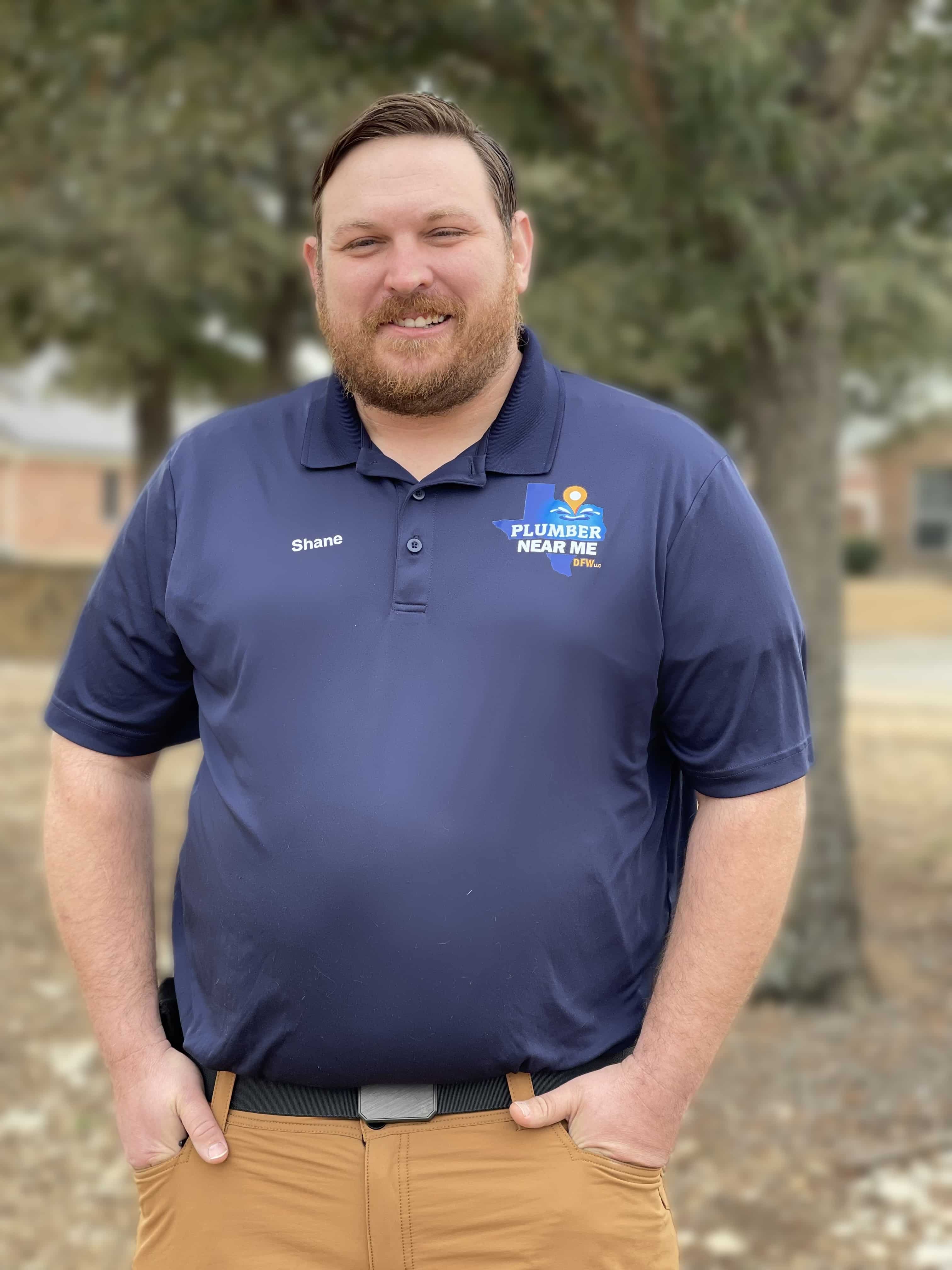 Professional plumber from Plumber Near Me DFW wearing branded shirt, smiling outdoors showcasing plumbing expertise and community service in Euless and Keller, TX.